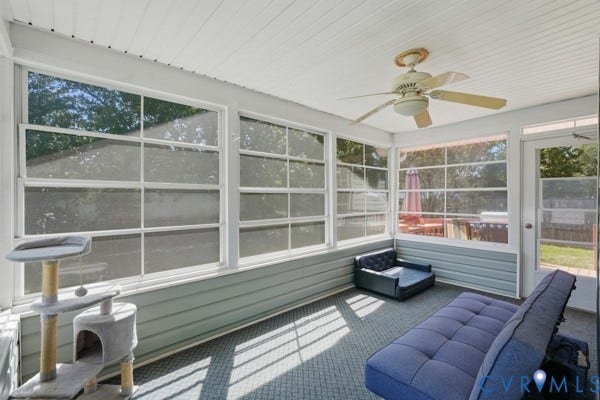 Screened-in porch featuring multiple windows, a ceiling fan, a paneled ceiling, and horizontal siding