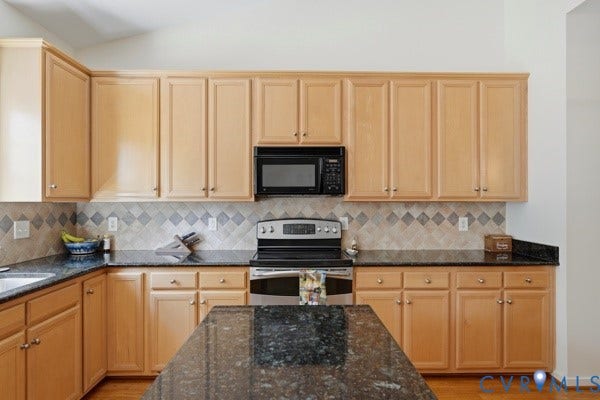 Recessed lighting, wood-finish flooring, ample cabinetry, dark stone countertops, and a tiled backsplash