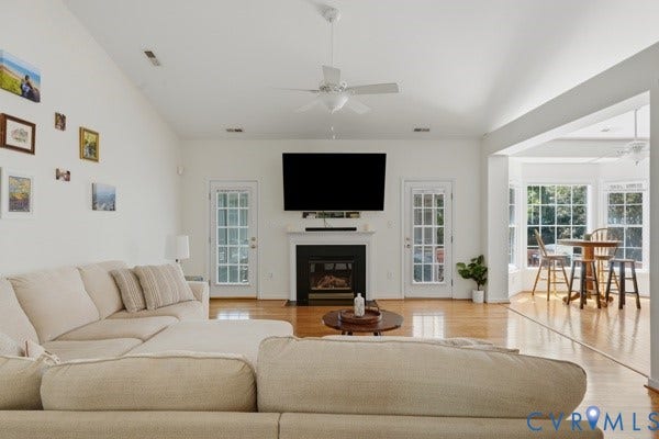 Vaulted ceilings complement the living area featuring a fireplace with a white mantel and two French doors