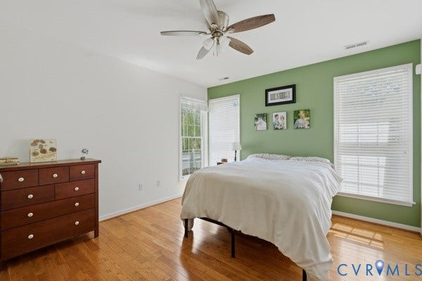 Hardwood-finish flooring, ceiling fan, and multiple windows with blinds