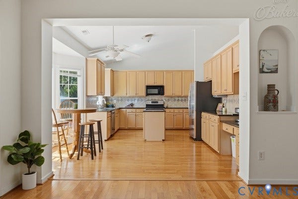 Kitchen featuring wood-finish flooring, light-toned cabinetry, stainless steel appliances, and a ceiling fan