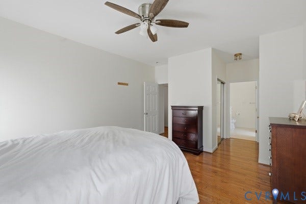Hardwood flooring, ceiling fan with integrated lighting, white walls, white trim, and a frosted glass-paneled closet door