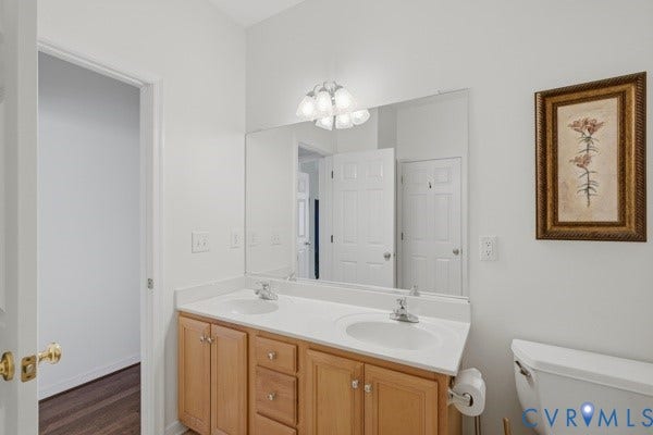 Dual vanity with wood-finish cabinetry, integrated sinks, and polished chrome fixtures