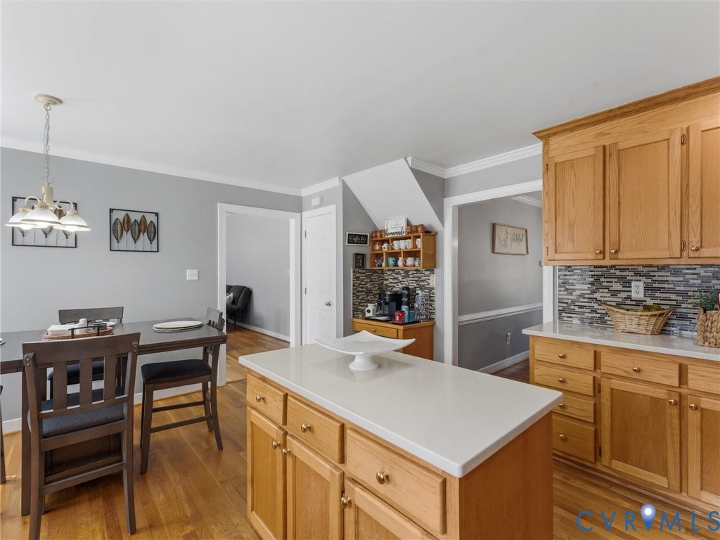 3489 Richards Run, Powhatan, VA 23139 Open-concept kitchen and dining area featuring warm wood cabinetry, white quartz countertops, mosaic tile backsplash, a center island with prep space, and hardwood flooring throughout