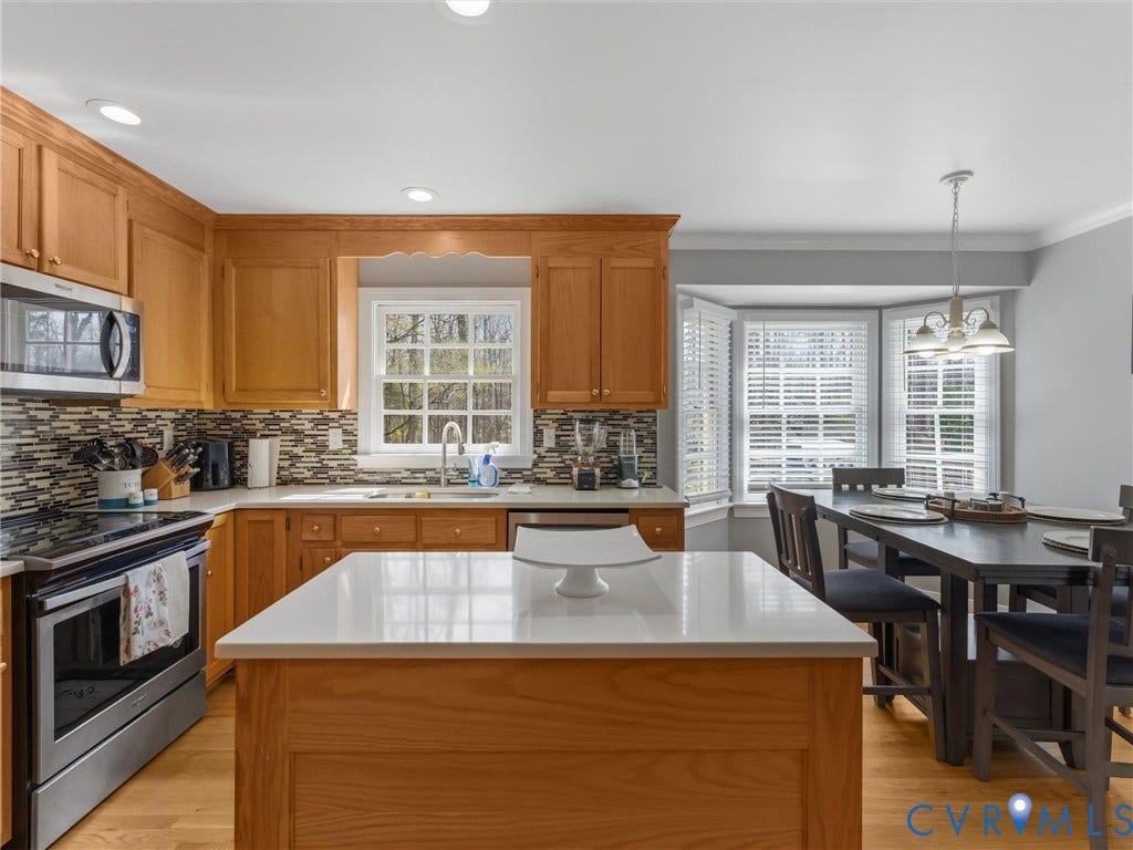 3489 Richards Run, Powhatan, VA 23139 Natural wood cabinetry, stainless steel appliances, mosaic tile backsplash, recessed lighting, and a bay window with blinds