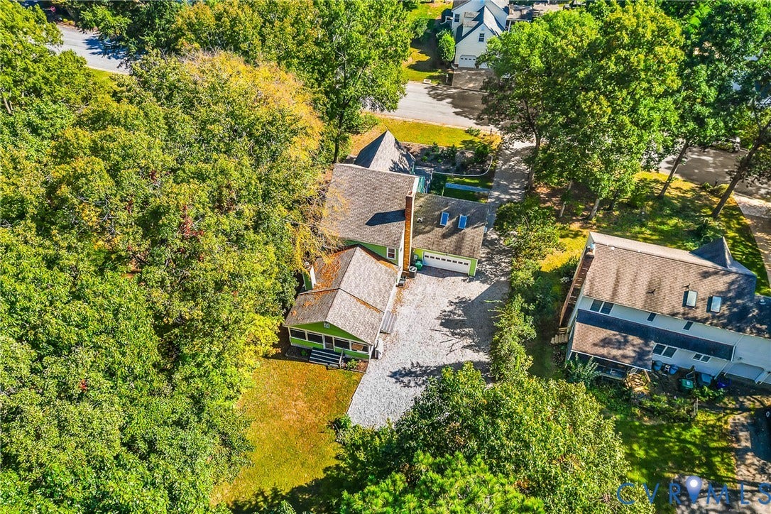 1608 Queens Point Drive, Henrico, VA 23238 Aerial perspective featuring a multi-gabled residence with a shingled roof, attached garage, screened porch, and a stone-surfaced driveway surrounded by mature wooded landscaping
