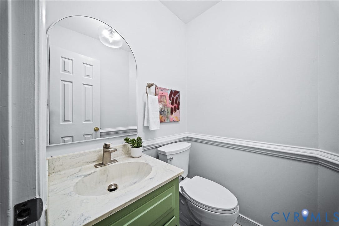 1608 Queens Point Drive, Henrico, VA 23238 Powder room featuring an arched wall mirror, vanity with a stone-composite countertop, oval undermount sink, brushed-nickel faucet, and chair rail molding