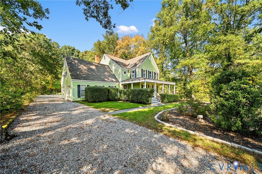 1608 Queens Point Drive, Henrico, VA 23238 Two-story residence featuring light green siding, dark shutters, an expansive wraparound front porch, and a stone-lined garden bed