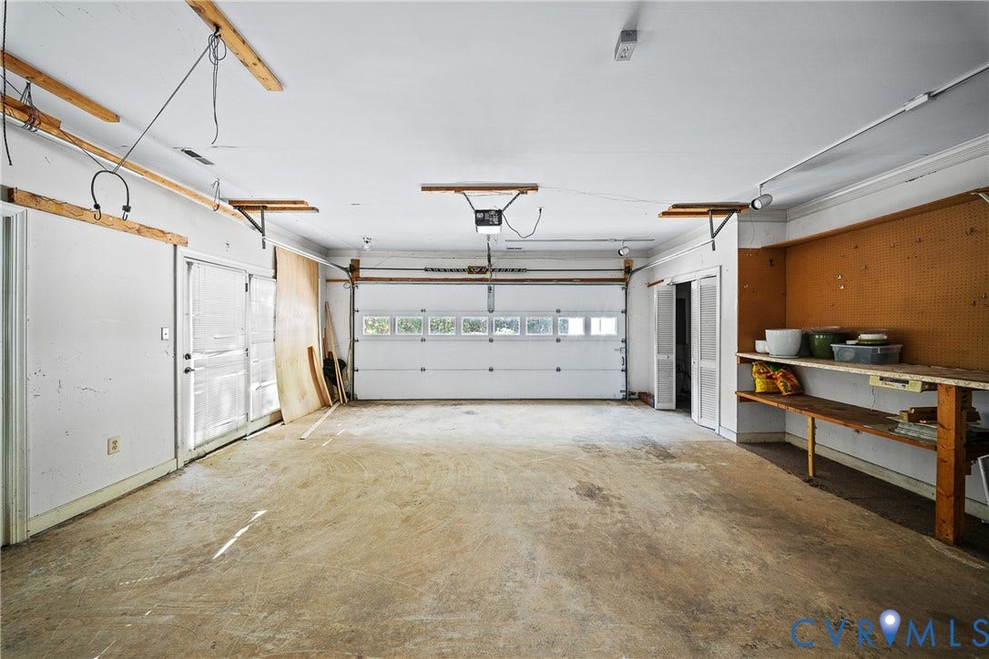 1608 Queens Point Drive, Henrico, VA 23238 Two-car garage featuring a sectional door with windows, built-in wooden shelving, pegboard wall organization, and a private side-entry door