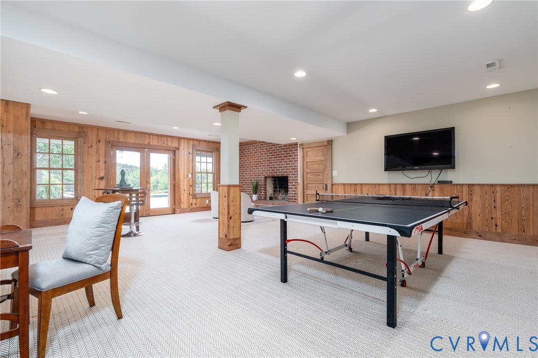 Recessed lighting illuminates the carpeted flooring and wood paneling