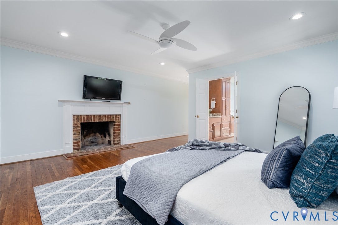 Hardwood flooring, brick fireplace with white mantel, recessed lighting, ceiling fan, and double doors to additional space