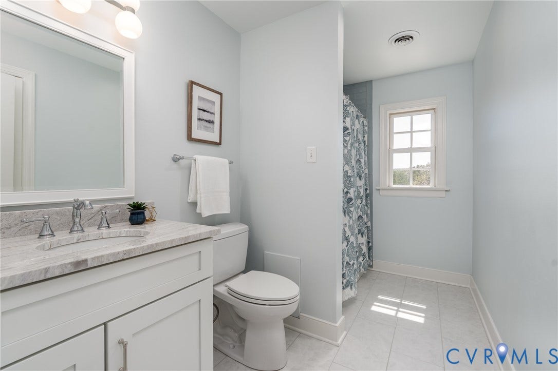 Bathroom featuring a single vanity with stone countertop, white cabinetry, integrated sink, and a framed mirror