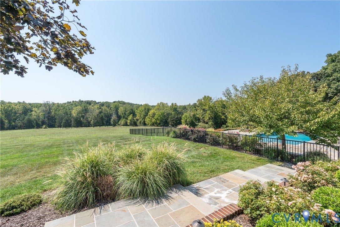 Expansive outdoor area featuring a swimming pool, stone patio, and a manicured lawn
