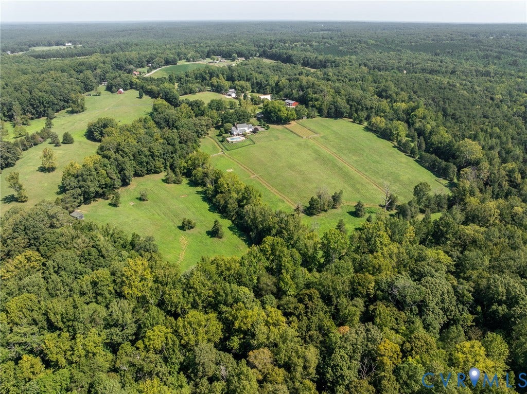 Expansive property featuring wooded areas, open fields, and multiple structures