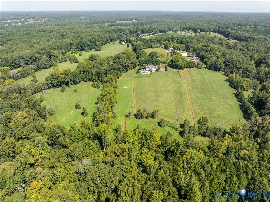 Expansive agricultural property featuring a primary residence, ancillary structures, and extensive wooded areas