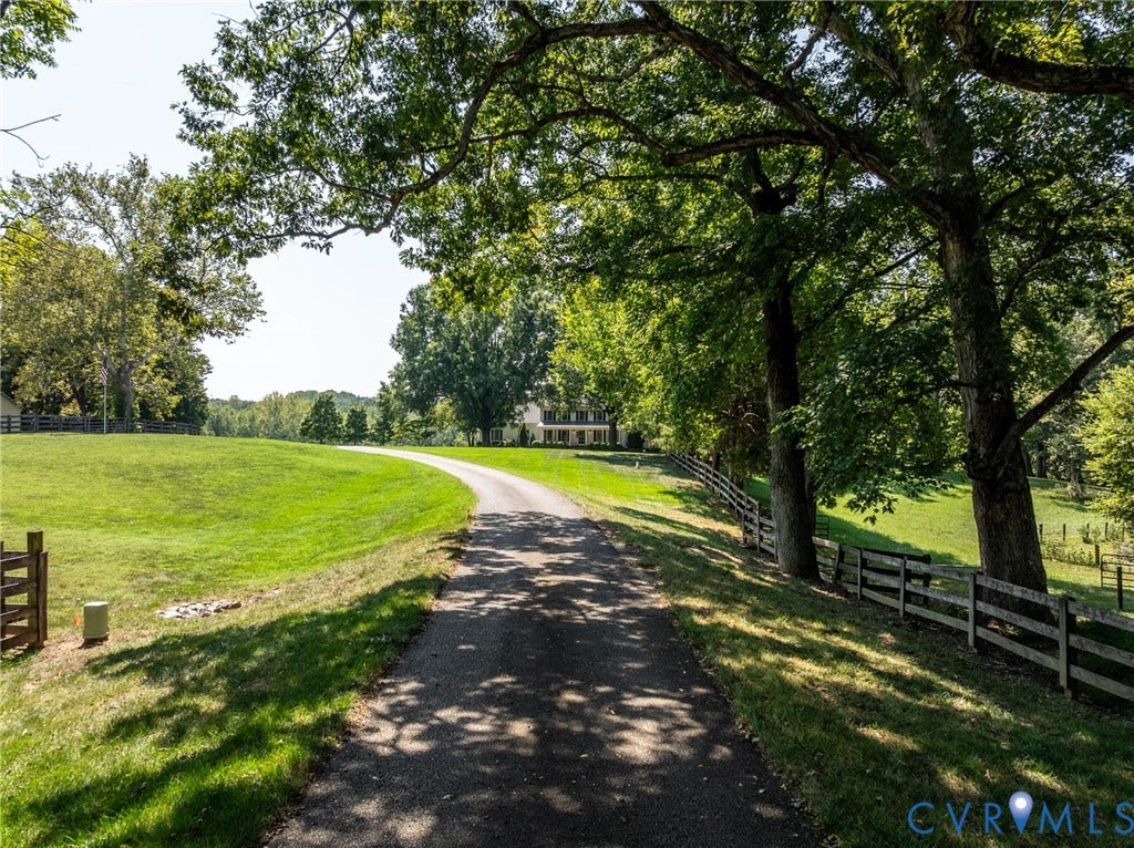 Paved driveway leading to the main residence, framed by mature trees and expansive green lawns