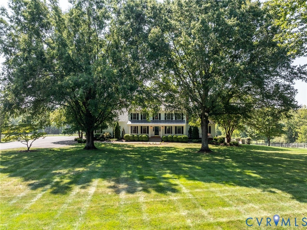 Expansive lawn with mature trees, a traditional-style residence, and established landscaping