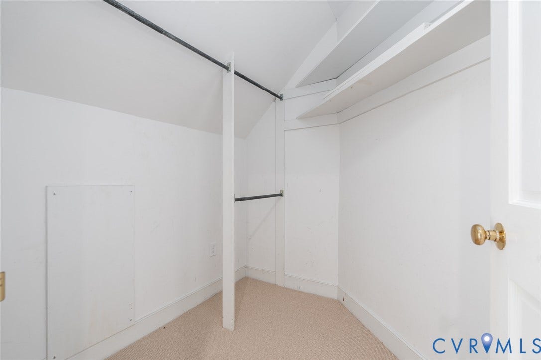 Built-in shelving, two hanging rods, and light-toned carpeting
