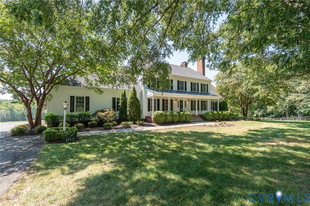 Two-story residence with white siding and dark shutters, featuring a columned front porch