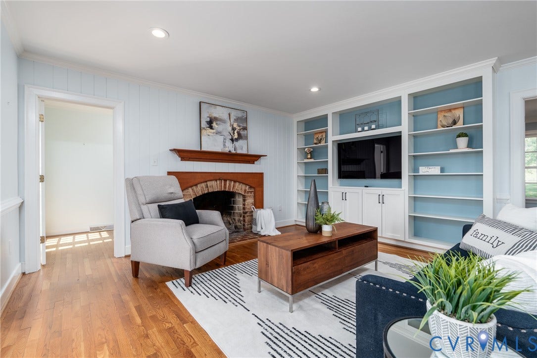 Hardwood flooring, recessed lighting, brick fireplace with a wood mantel, and built-in shelving with cabinetry