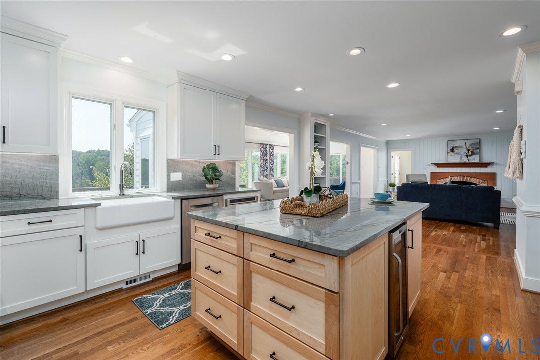 Kitchen featuring white shaker cabinetry, an apron-front sink, a central island with wood finish cabinetry, and integrated stainless steel appliances