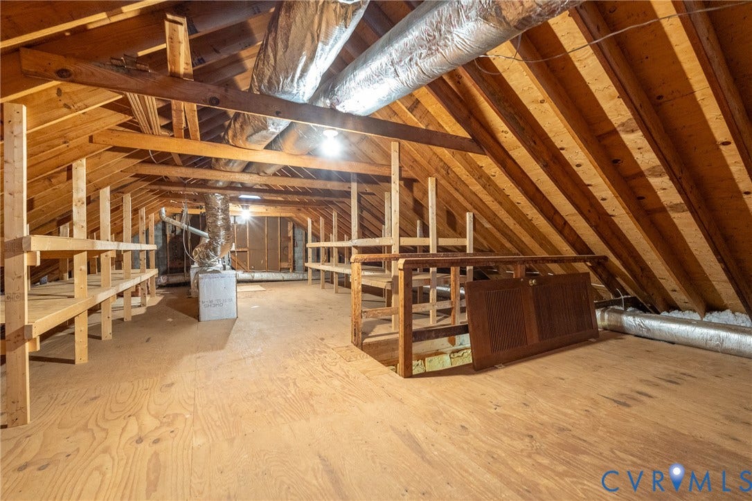 Spacious attic with exposed wood framing, wood-finish flooring, and built-in shelving units