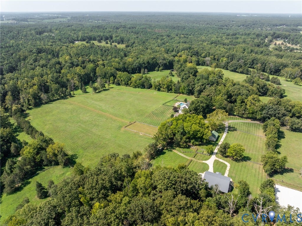 Expansive acreage featuring multiple structures, open fields, and wooded areas