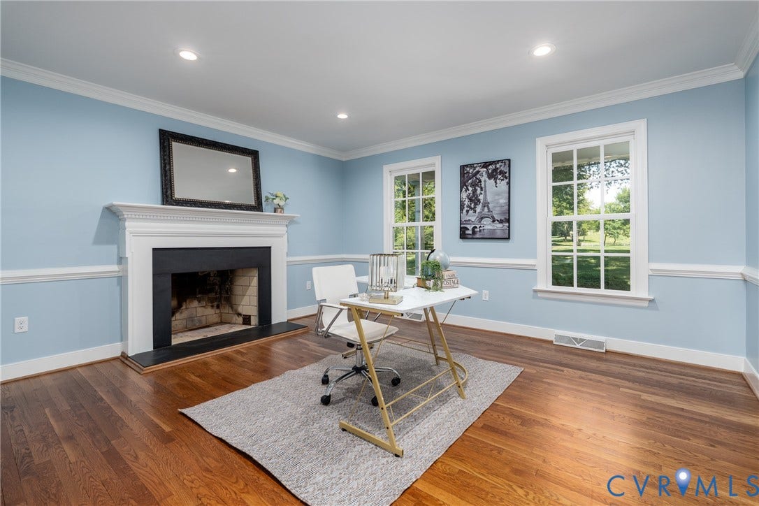 Hardwood flooring, crown molding, chair rail molding, recessed lighting, and a fireplace with a white mantel and black surround