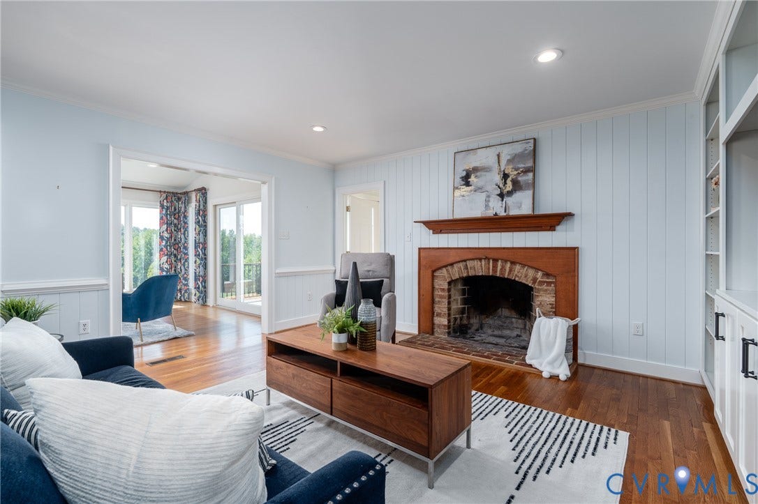 Hardwood flooring, brick fireplace with wood mantel, built-in shelving with lower cabinetry, recessed lighting, and a doorway leading to an exterior balcony