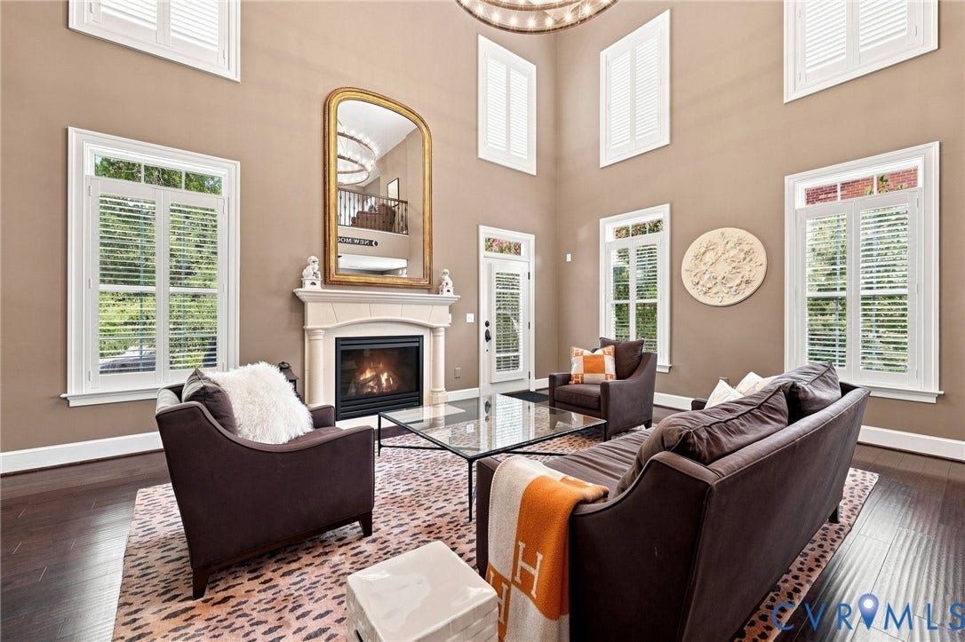 11762 Triple Notch Terrace, Three Notch Place, Henrico, VA 23233 Soaring ceilings with upper-level windows, a stone-surround fireplace, dark wood-finish flooring, and white plantation shutters on multiple windows