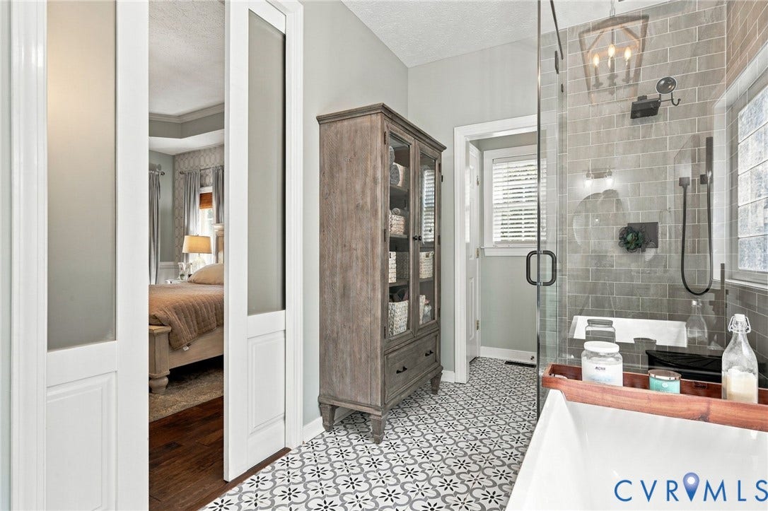 8301 Macandrew Terrace, Chesterfield, VA 23838 Patterned floor tiling, glass-enclosed shower, subway tile shower surround, freestanding soaking tub, wood-finish storage cabinet