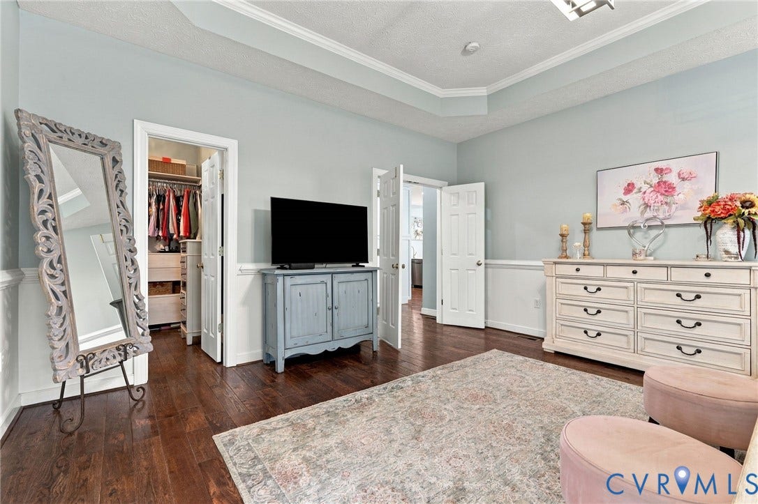 8301 Macandrew Terrace, Chesterfield, VA 23838 Tray ceiling with crown molding, light blue wall paint, chair rail molding, dark wood-finish flooring, and a walk-in closet with built-in shelving