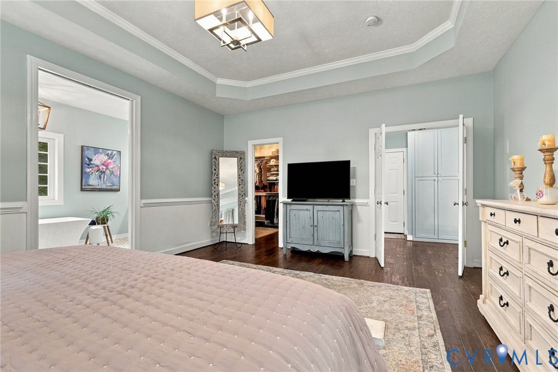 8301 Macandrew Terrace, Chesterfield, VA 23838 Tray ceiling with crown molding, wood-finish flooring, half wall paneling, built-in storage cabinetry, and an interior doorway leading to an additional space
