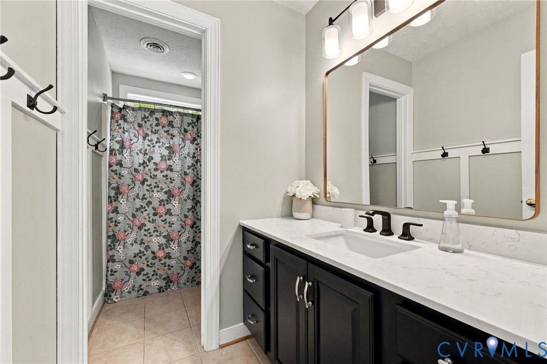 8301 Macandrew Terrace, Chesterfield, VA 23838 Vanity featuring a white countertop with an integrated sink, dark cabinetry, and black fixtures