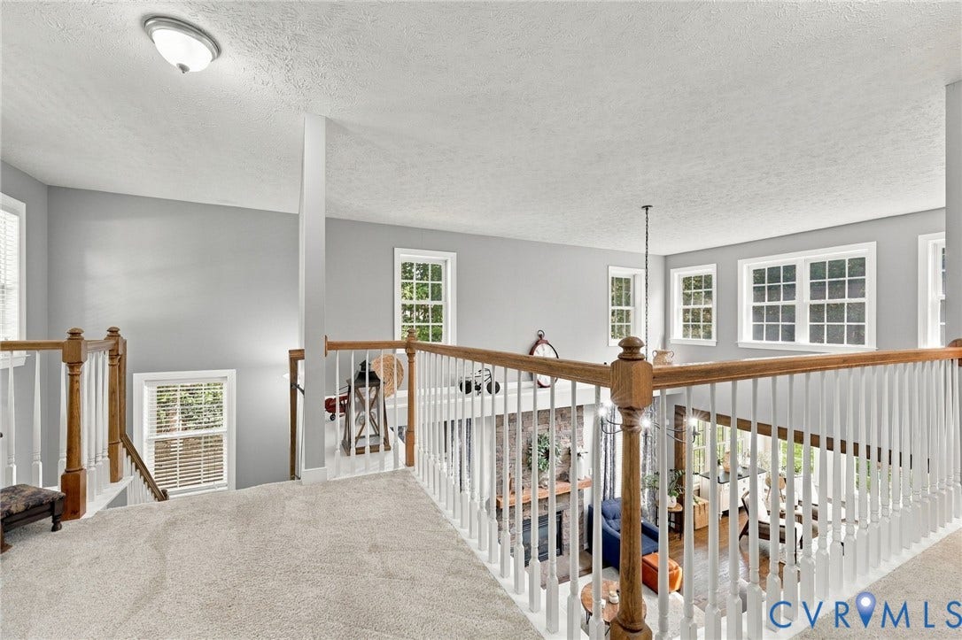 8301 Macandrew Terrace, Chesterfield, VA 23838 Carpeted landing featuring a wood and white spindle railing, multiple windows with white trim, and light gray wall finishes