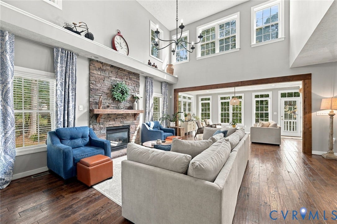 8301 Macandrew Terrace, Chesterfield, VA 23838 Two-story living area featuring a stone fireplace with a wood mantle, hardwood flooring, and multiple large windows