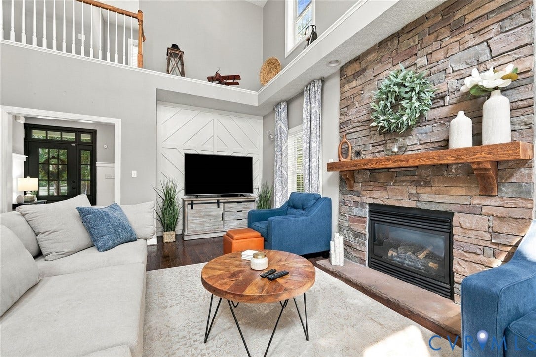 8301 Macandrew Terrace, Chesterfield, VA 23838 Stone-faced fireplace with a wood mantel, wood-finish flooring, and a two-story ceiling