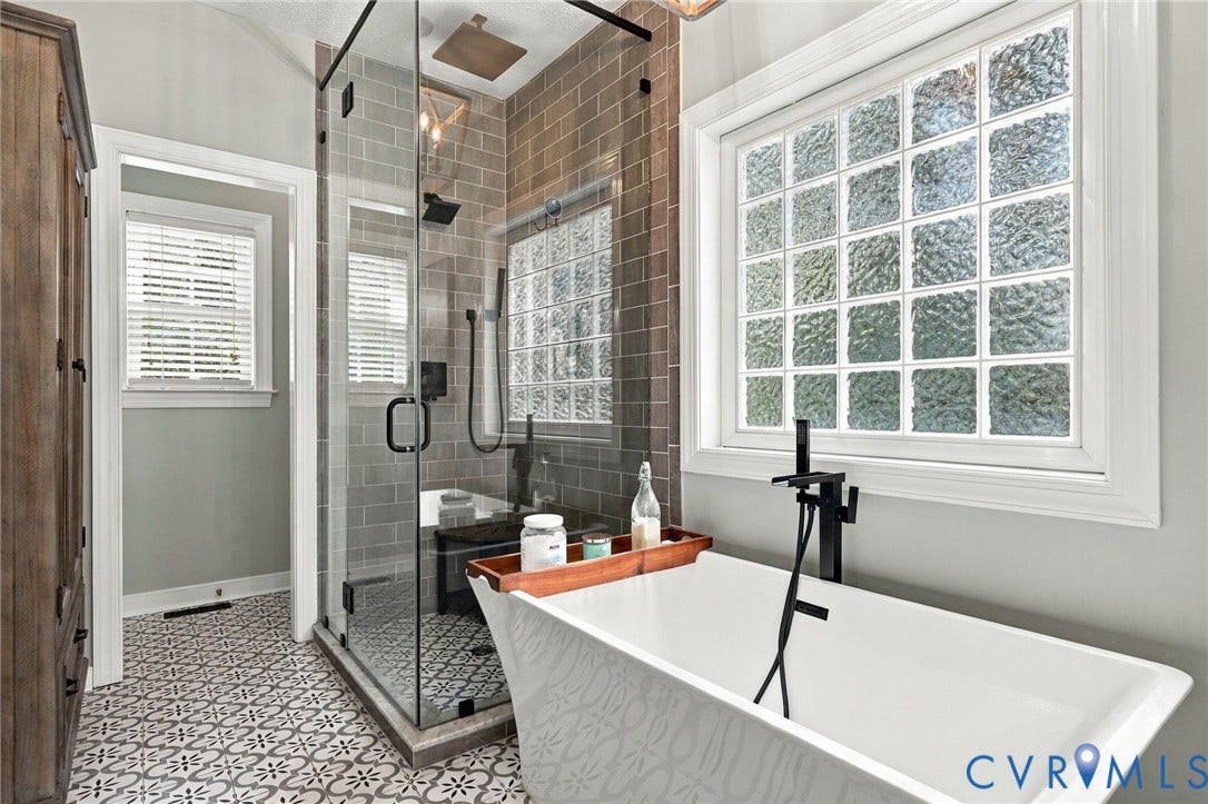 8301 Macandrew Terrace, Chesterfield, VA 23838 Freestanding soaking tub with a floor-mounted matte black faucet, glass block window, walk-in shower with tile surround, and patterned floor tile