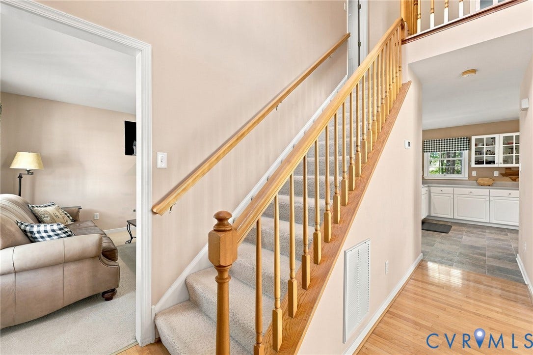 12309 Maybrook Lane, Wyndham, Glen Allen, VA 23059 Hardwood flooring, carpeted staircase with wood banister, and a kitchen featuring white cabinetry and a window