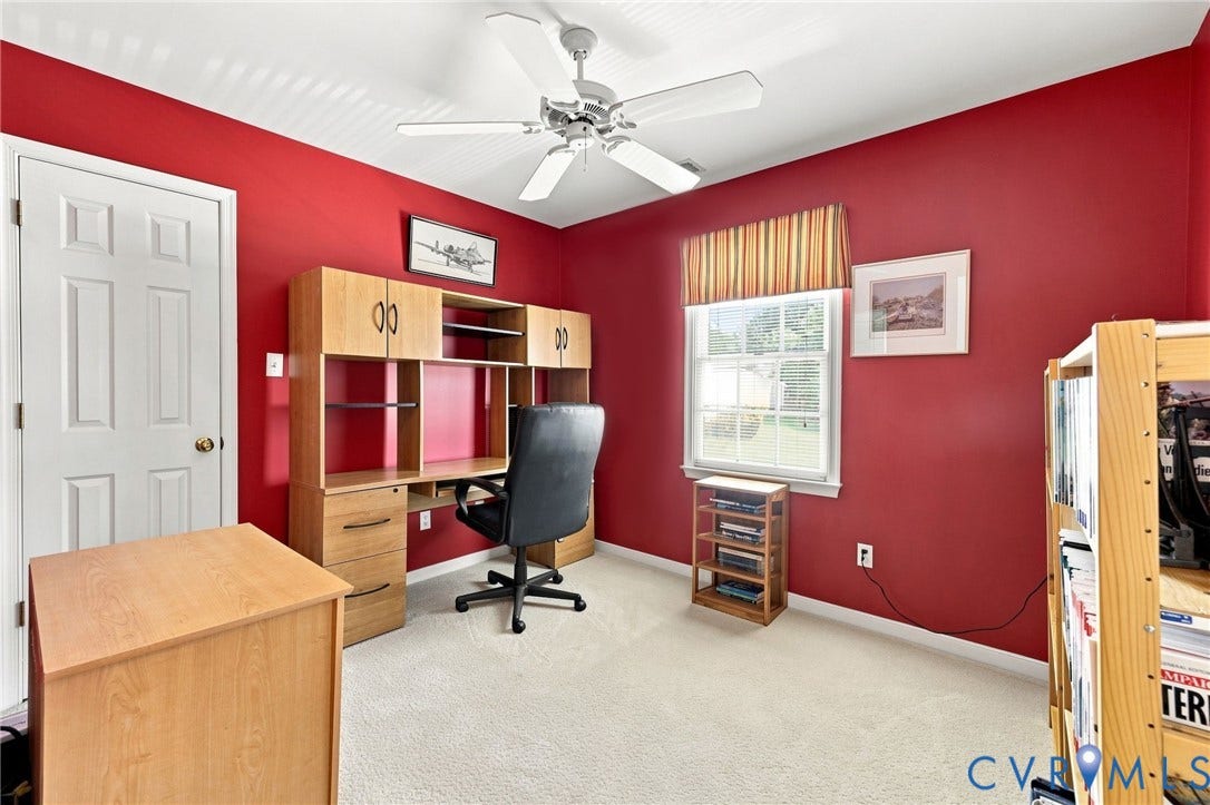 12309 Maybrook Lane, Wyndham, Glen Allen, VA 23059 Bright, versatile bedroom featuring vibrant red walls, wood-finish cabinetry with built-in shelving and storage, carpet flooring, ceiling fan, and abundant natural light from large windows