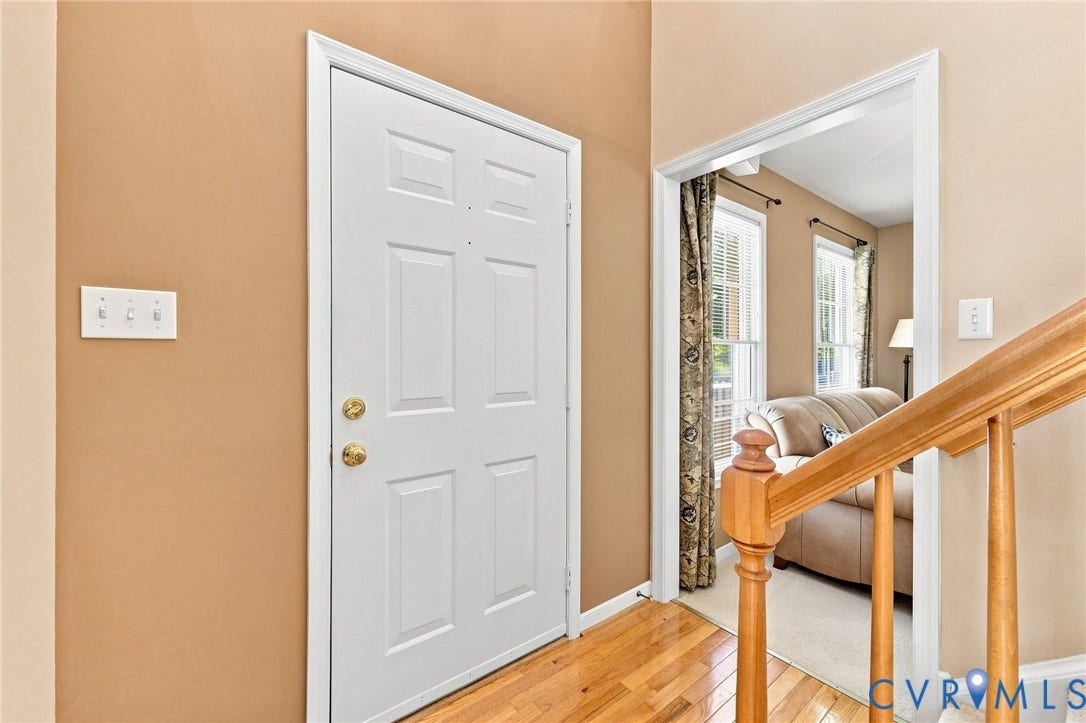 12309 Maybrook Lane, Wyndham, Glen Allen, VA 23059 White paneled entry door with brass hardware, wood-finish flooring, and a natural wood staircase railing