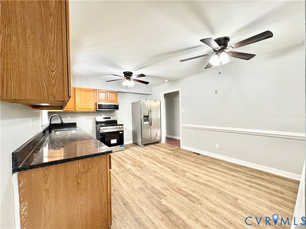 2711 Cheatham Street, Henderson & Johnson, Richmond, VA 23234 Kitchen and dining area featuring wood-finish flooring, dark stone countertops, wood cabinetry, and stainless steel appliances