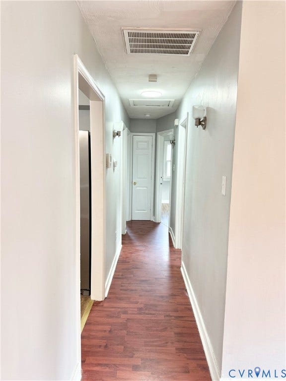 2711 Cheatham Street, Henderson & Johnson, Richmond, VA 23234 Hallway featuring wood-finish flooring, light grey walls, white trim, and wall-mounted sconces