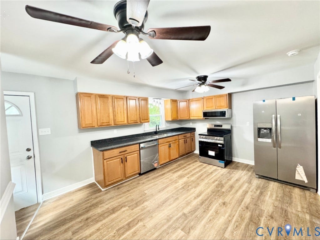 2711 Cheatham Street, Henderson & Johnson, Richmond, VA 23234 Kitchen featuring wood-finish flooring, light wood cabinetry, dark countertops, and stainless steel appliances