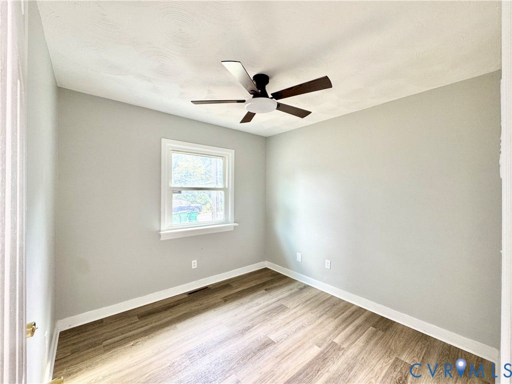 2711 Cheatham Street, Henderson & Johnson, Richmond, VA 23234 Bright bedroom showcasing wood-finish flooring, neutral painted walls, and a ceiling fan with integrated lighting
