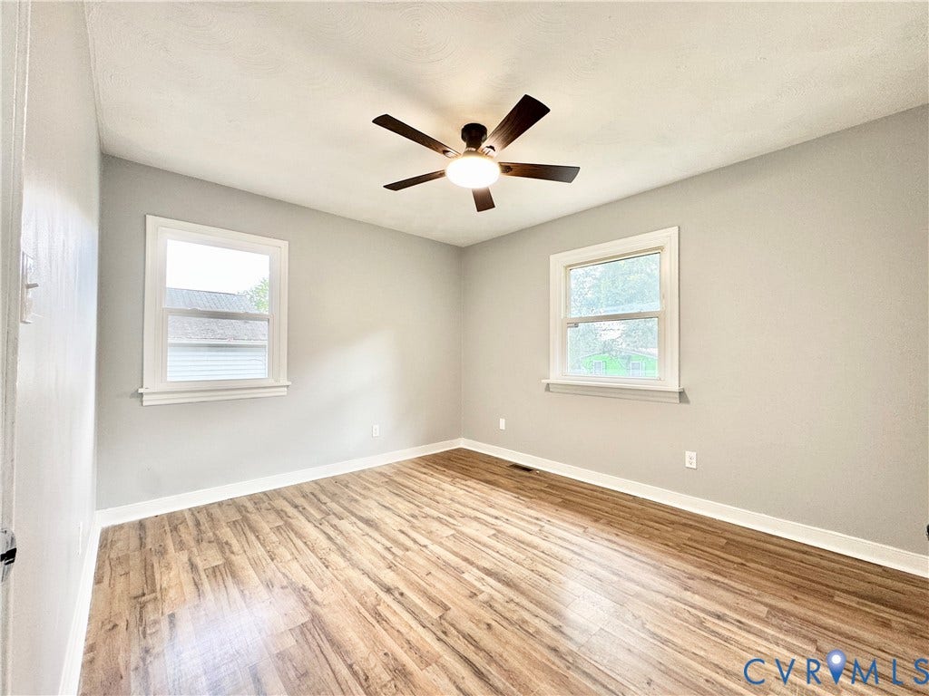 2711 Cheatham Street, Henderson & Johnson, Richmond, VA 23234 Wood-finish flooring, two large windows, neutral wall tones, and a ceiling fan with integrated lighting