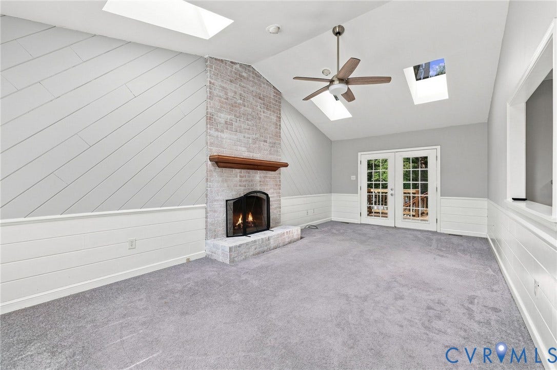 608 Dauphin Drive, Chesterfield, VA 23236 Vaulted ceiling with skylights, whitewashed brick fireplace with wood mantel, diagonal wood-paneled accent wall, and glass-paneled French doors