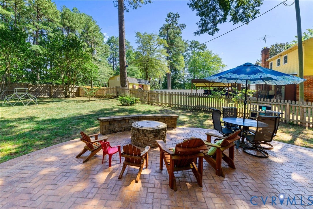 1109 Swissvale Place, Henrico, VA 23229 Expansive backyard featuring a stamped concrete patio, stone fire pit, and wood picket fencing