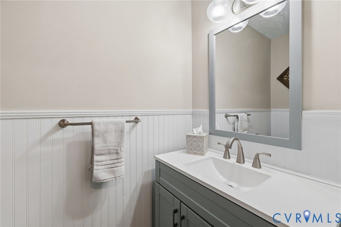 1109 Swissvale Place, Henrico, VA 23229 Vanity with integrated sink, brushed nickel faucet, framed mirror, and beadboard wainscoting