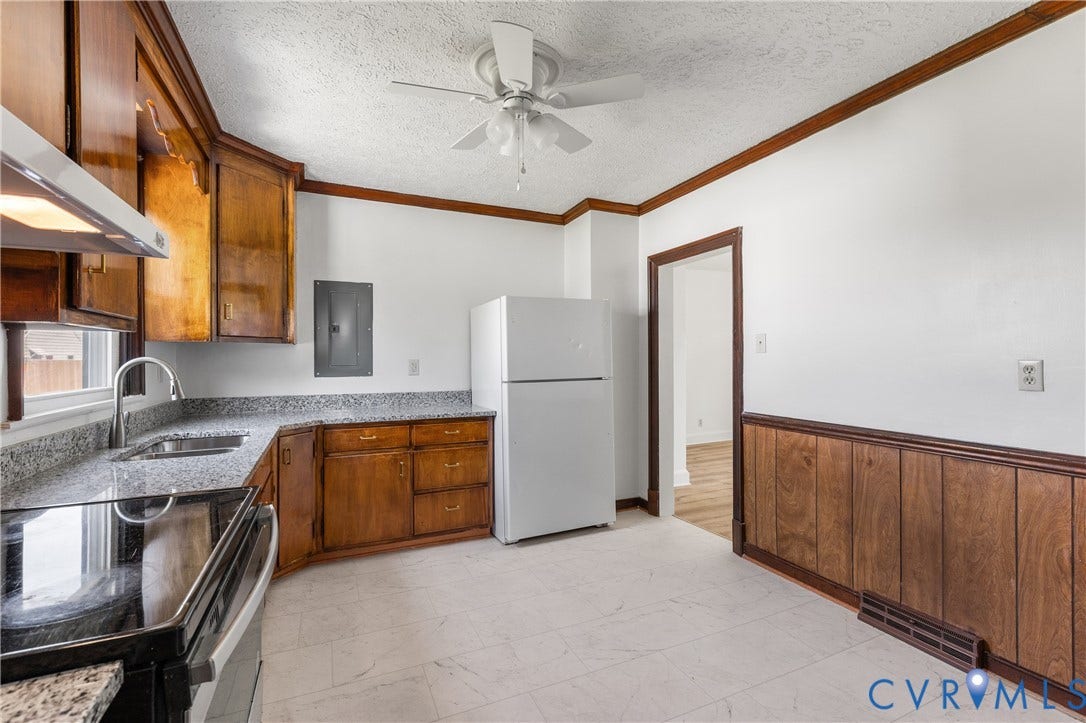 Kitchen featuring wood cabinetry, granite-style countertops, stainless steel sink, and a ceiling fan